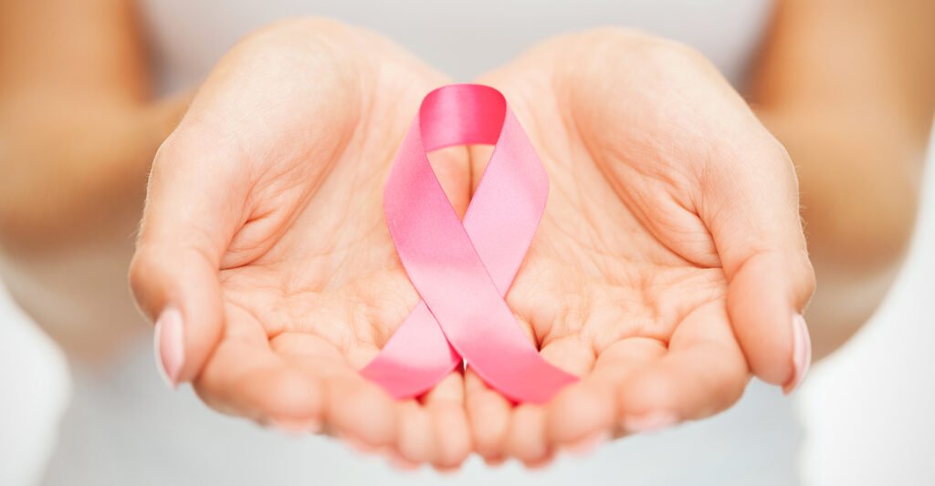 Open hands holding a pink ribbon